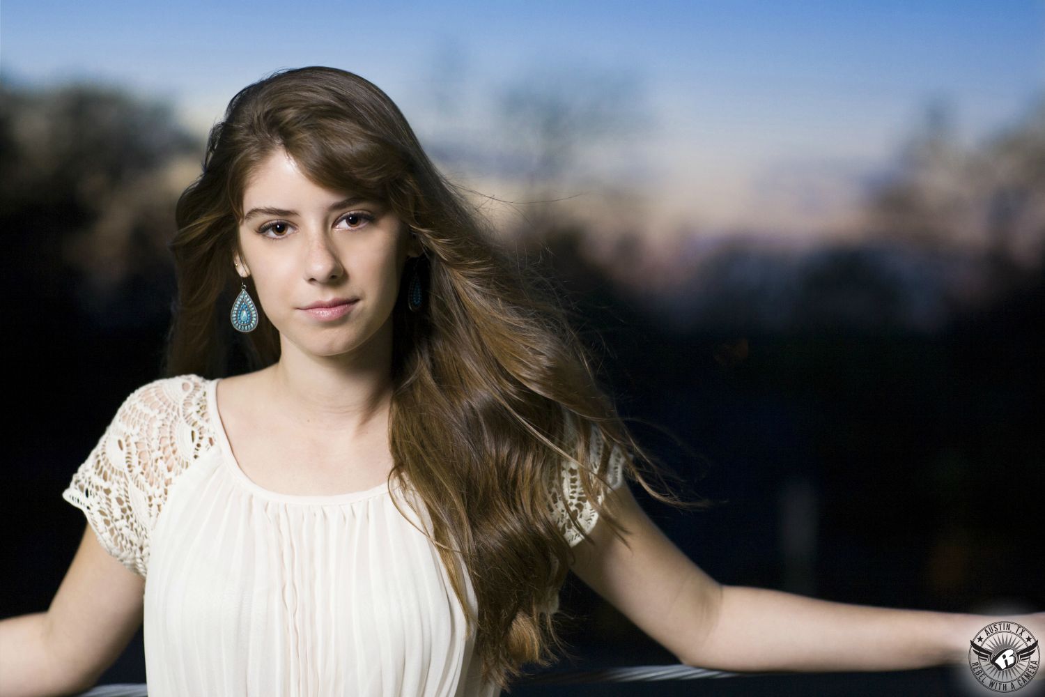 Best senior photos in Austin of girl in white dress with dramatic sunset behind.